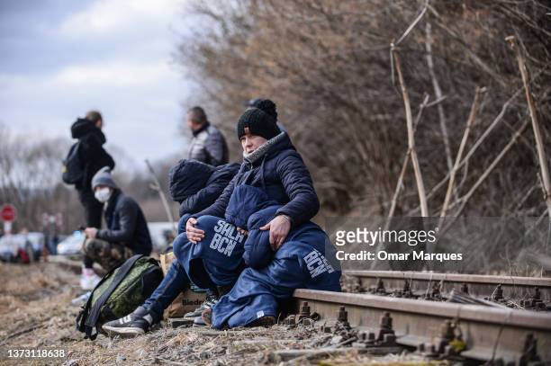 People take a rest on a train line after arriving in Poland next to a border check point on February 27, 2022 in Kroscienko, Poland. More than 156,...