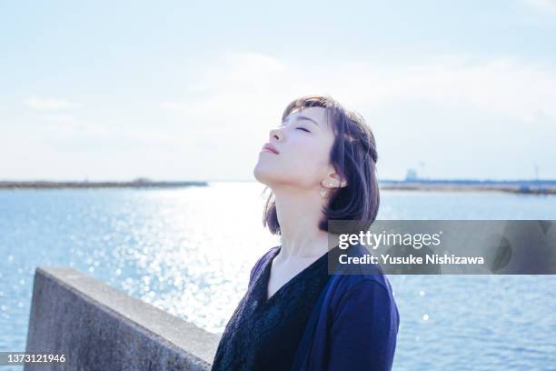 a pensive woman with her eyes closed - japanese woman looking up stockfoto's en -beelden