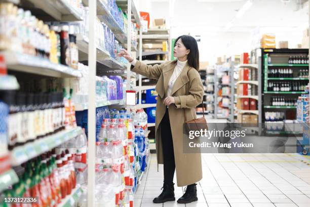 full body portrait of a young asian woman buying purified water in a supermarket - purified water stockfoto's en -beelden