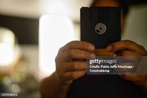 young man holds a diskette - diskette stock pictures, royalty-free photos & images