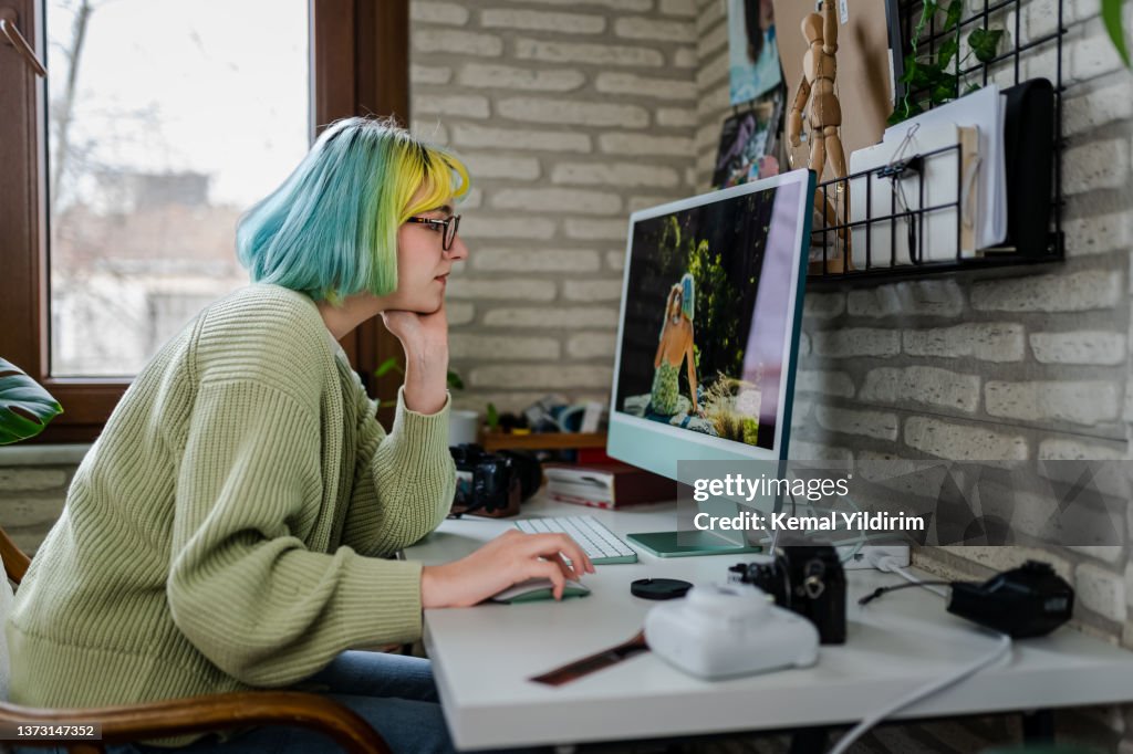 Millennial-Fotografin, die im Home Office an ihren Fotos arbeitet