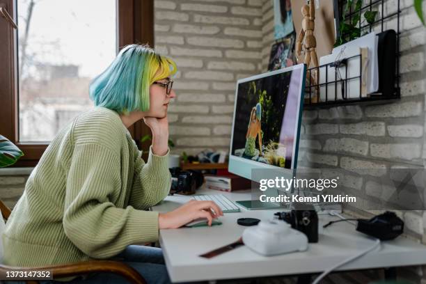 fotografa millennial che lavora alle sue foto in home office - redattore iconografico foto e immagini stock