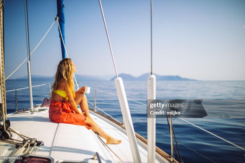 Young attractive woman enjoying at sunny day on yacht
