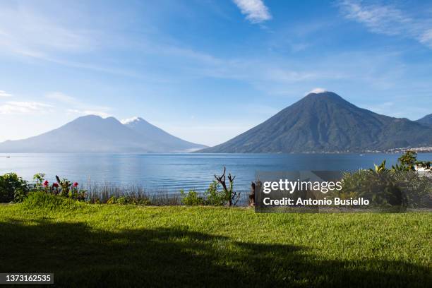 view of volcán san pedro, volcán tolimán, and volcán atitlán on lake atitlán from san marcos la laguna - san marcos guatemala stock pictures, royalty-free photos & images