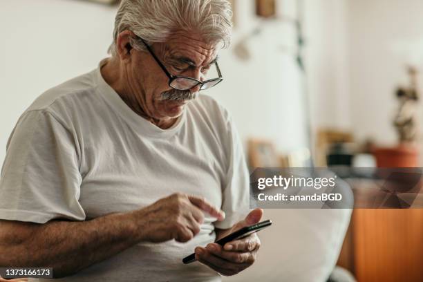 portrait of  senior man sitting in his living room - only senior men stock pictures, royalty-free photos & images