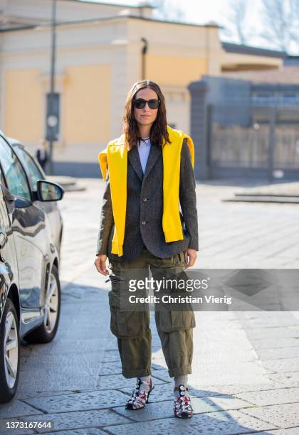 Erika Boldrin seen wearing yellow jumper over shoulder, olive cargo pants with zipper pockets, grey blazer, sunglasses, heels, grey socks outside...