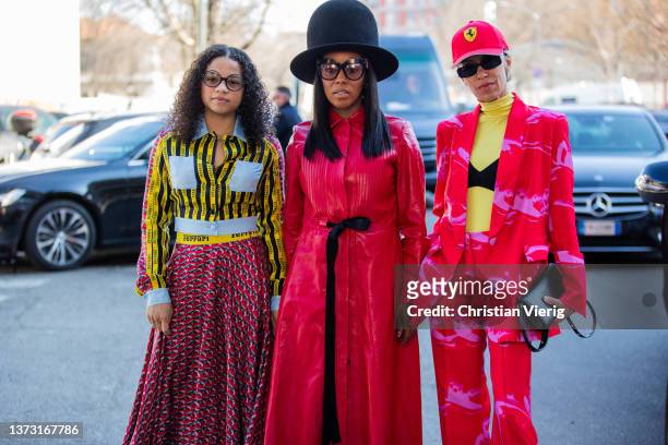 Guest is seen wearing big black hat, red coat and a guest wearing skirt, yellow black striped button shirt outside Ferrari during the Milan Fashion...