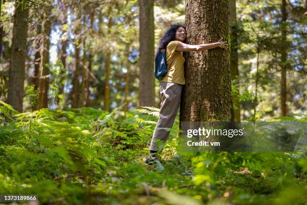 female nature lover embracing tree in forest - eco activist stock pictures, royalty-free photos & images