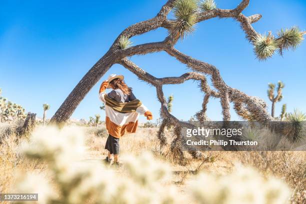 mulher vagando com roupas coloridas na área deserta do parque nacional joshua tree em um dia ensolarado do céu azul - joshua tree - fotografias e filmes do acervo