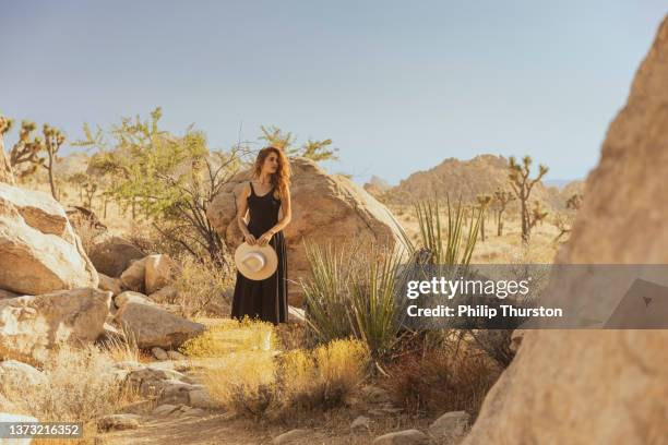 beautiful woman in dress standing in bright desert sun at joshua tree national park - beige fashion stock pictures, royalty-free photos & images