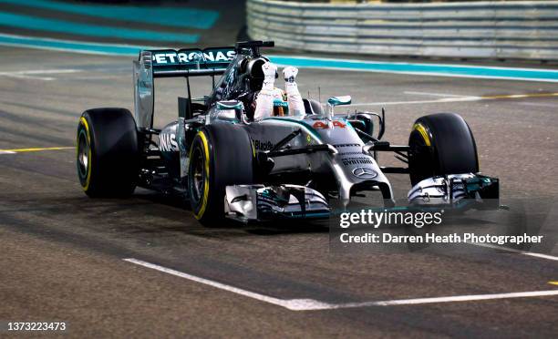 British Mercedes-AMG Formula One racing team racing driver Lewis Hamilton driving his F1 W05 racing car at speed across the finish line while raising...