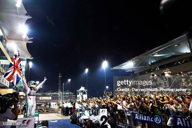 Standing on his Mercedes-AMG F1 W05 racing car in Parc Fermé while wearing his logo adorned fire protection suit racing driver overalls and waving a...