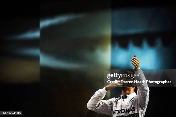 Standing on the winners podium wearing his logo adorned fire protection suit racing driver overalls and a Pirelli cap, British Mercedes-AMG Formula...