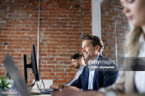 happy businessman working on pc with his colleagues in the office. - business casual dress code stock pictures, royalty-free photos & images