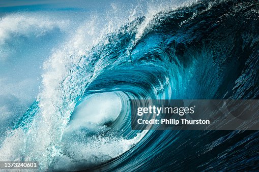 Close up detail of powerful teal blue wave breaking in open ocean on a bright sunny afternoon Close up detail of powerful teal blue wave breaking in open ocean on a bright sunny afternoon
