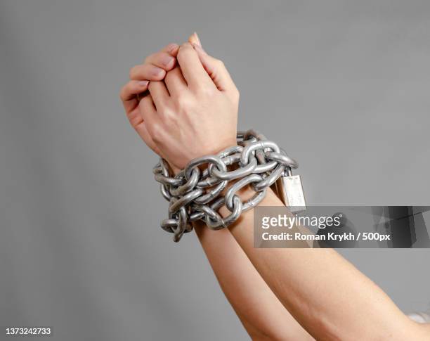 womans hands are tied with a shiny metal chain - hands tied up stock pictures, royalty-free photos & images