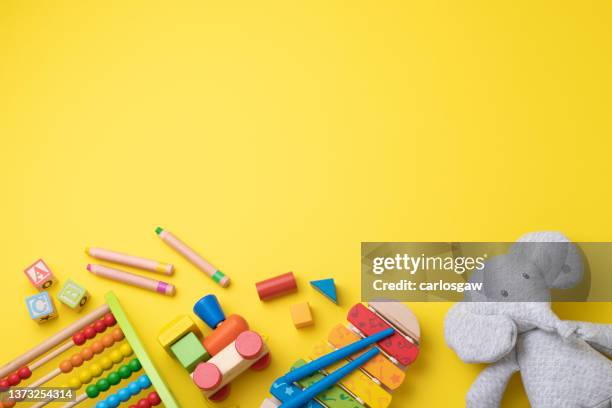 assortment of toddler toys with copy space on yellow background - kids background stock pictures, royalty-free photos & images