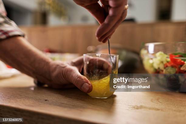pareja de ancianos preparando una ensalada de verduras saludable en casa. - aliño para la ensalada fotografías e imágenes de stock