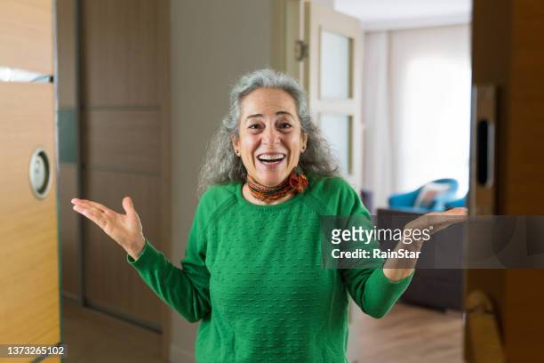 senior woman opening the front door is surprised with happiness - woman standing in doorway stock pictures, royalty-free photos & images