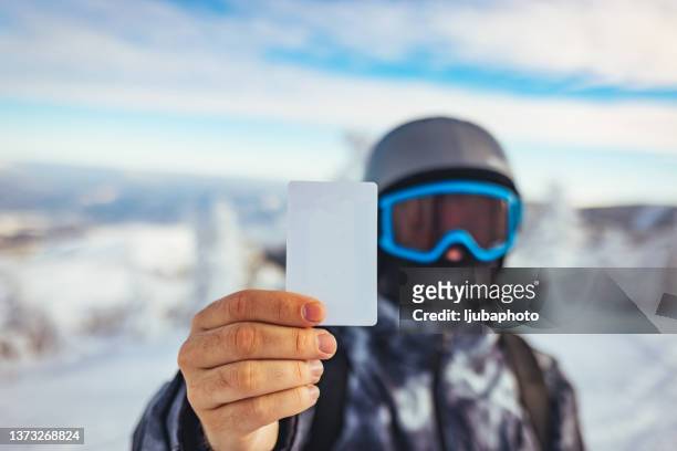 young man holding blank ski lift pass looking - voucher card imagens e fotografias de stock