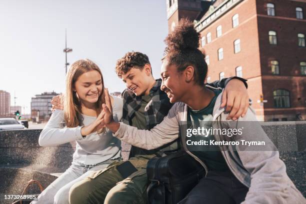 portrait of three teenager friends hangin out together down town - boys and girls town stockfoto's en -beelden