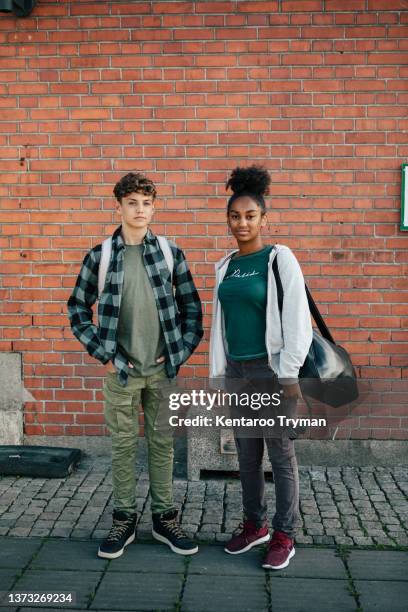 portrait of two teenagers standing in front of a brick wall - serious teenager boy imagens e fotografias de stock