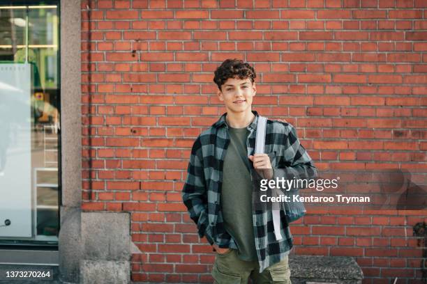 portrait of a smiling teenage boy standing in front of a brick wall - one teenage boy only stock pictures, royalty-free photos & images