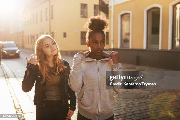 two teenage girls on a city street in back light - skane stockfoto's en -beelden