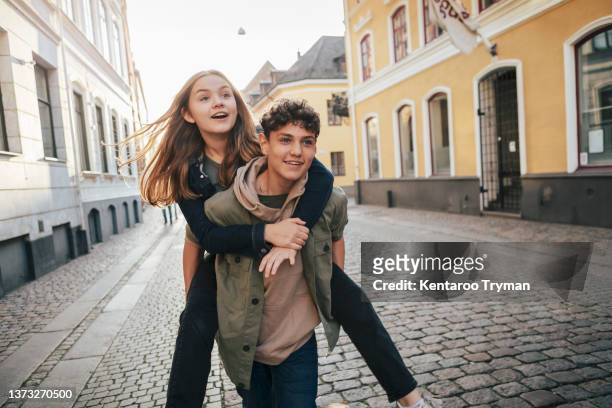 a teenage girl riding on the back of a boy friend - young love stock-fotos und bilder
