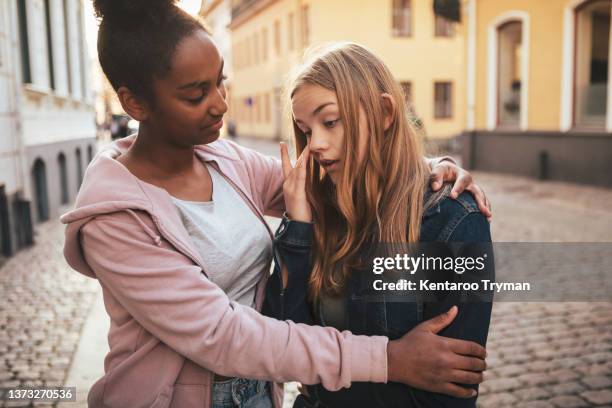 a teenage girl hugging her sad friend in city environment - emotional intelligence stock pictures, royalty-free photos & images