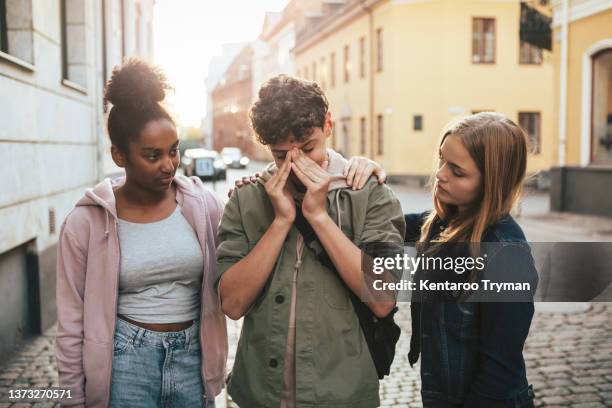 two teenage girls comfort their friend, in city environment - consoling teenager stock pictures, royalty-free photos & images