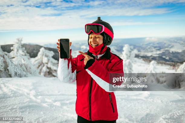 junge skifahrerin mit skibrille und smartphone - skifahrer stock-fotos und bilder