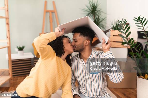 portrait of a happy couple  holding a book like a rooftop above their heads and kissing - new media imagens e fotografias de stock