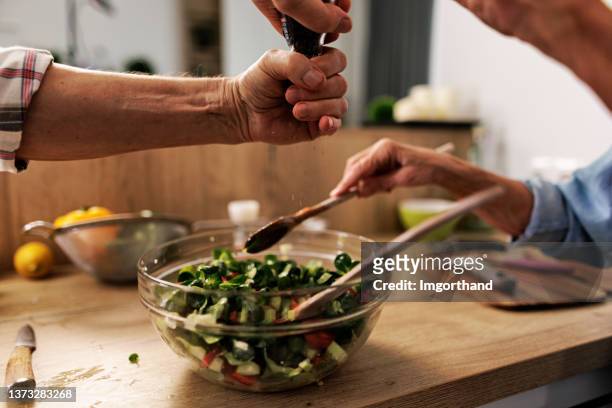 家庭で健康的な野菜サラダを準備するシニアカップル。 - sprinkling ストックフォトと画像