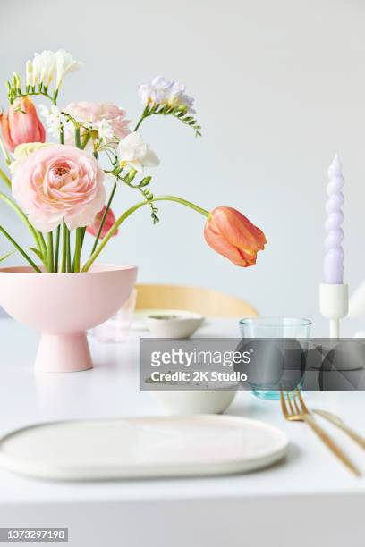 ein moderner frühlingsstrauß mit freesien, ranunkeln und tulpen in einer schönen vase - blumen als accessoire stock-fotos und bilder