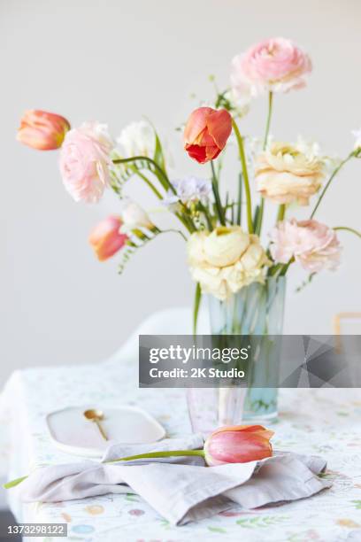 ein moderner frühlingsstrauß aus freesien, ranunkeln und tulpen in einer schönen vase - blumen als accessoire stock-fotos und bilder