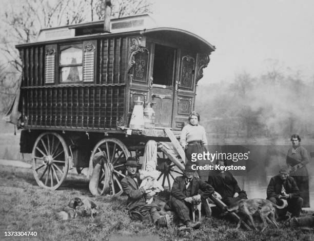 Family with their dogs and caravan near a river, UK, circa 1930.