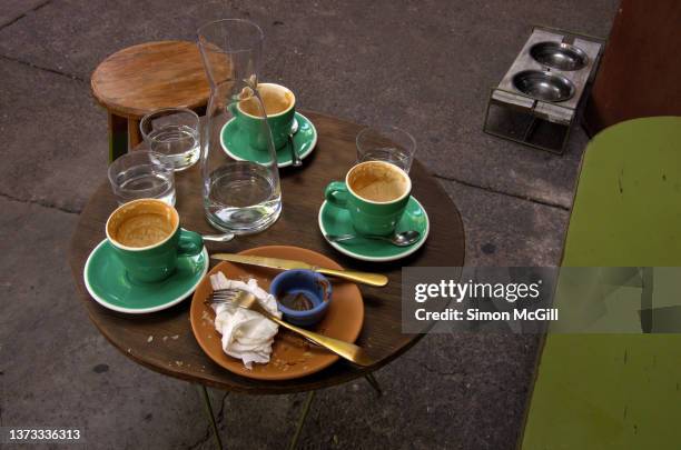 messy inner city sidewalk cafe table after coffees and a snack have been finished - early termination foto e immagini stock