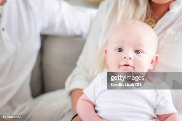 happy three month old adorable baby boy in a white onesie sitting in his mother’s lap - eye color stock pictures, royalty-free photos & images