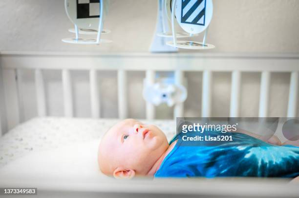 cute 3 month old baby boy relaxing laying down in crib looking at mobile - boy lying down stock pictures, royalty-free photos & images
