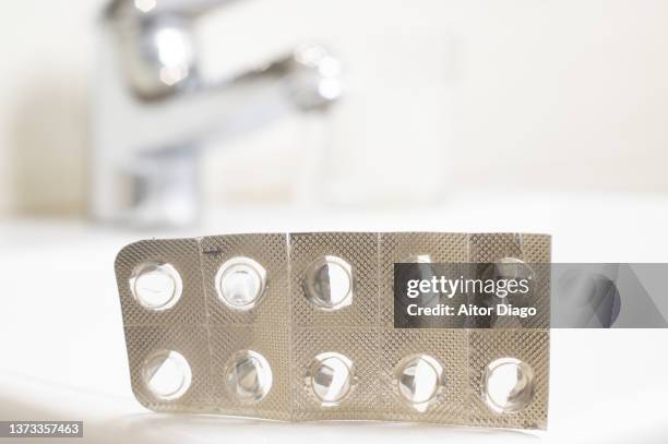 empty packaging of  encapsulated pills on the sink of a toilet. - sold out stockfoto's en -beelden