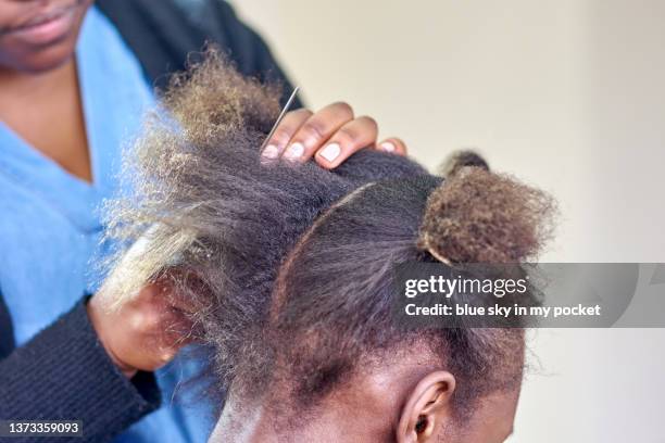 a young woman having her hair braided - flat iron stock pictures, royalty-free photos & images