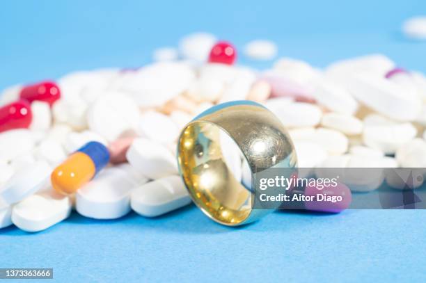 gold wedding band close to many pills. - ibuprofen stock pictures, royalty-free photos & images