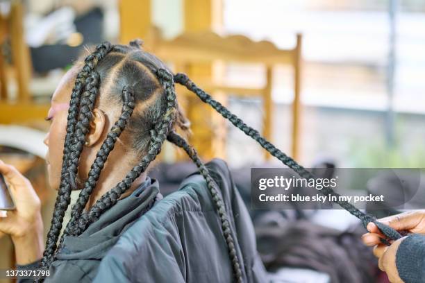 a young woman having her hair braided - gevlochten haar stockfoto's en -beelden