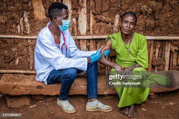 doctor is doing an injection to senior african woman in small village, east africa - doctors without borders 個照片及圖片檔