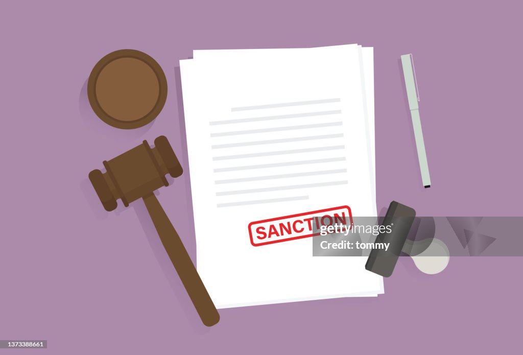 Document with a sanction sign, pen, rubber stamp, and a gavel on the table
