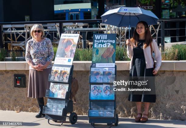smiling jehovah's witnesses standing next to their jehovah witness books and pamphlets - jehovah's witnesses stockfoto's en -beelden