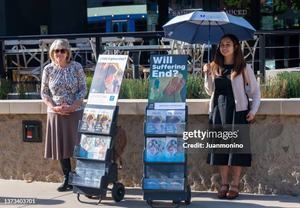 smiling jehovah's witnesses standing next to their jehovah witness books and pamphlets - testemunha imagens e fotografias de stock