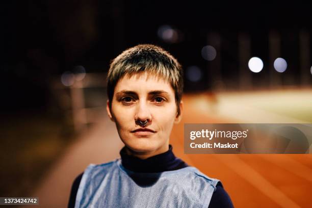 portrait of confident female athlete with short dyed hair on field - headshots soccer stock-fotos und bilder