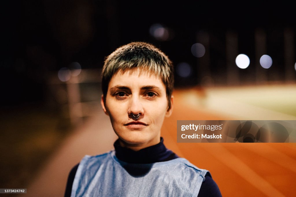 Portrait of confident female athlete with short dyed hair on field